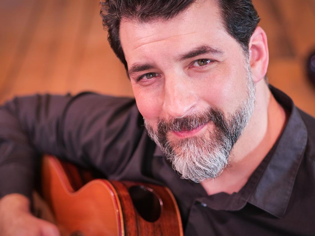 Matthew Cochran smiling, holding his guitar