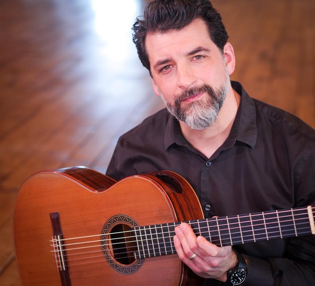 Matthew Cochran seated with his guitar